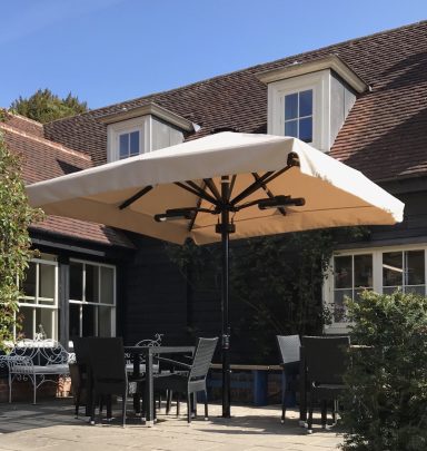 Patio with a large umbrella over a dining set, beside a house with a sloped roof.