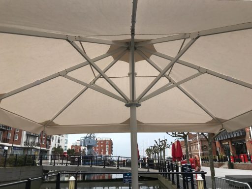 View of a large canopy structure against a background of a canal and buildings.