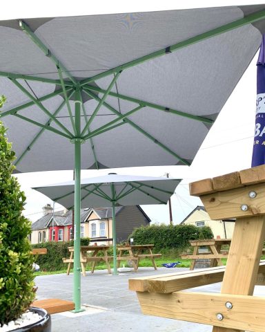 Outdoor seating area with large grey umbrellas and wooden benches.