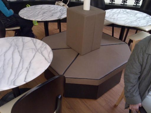 Hexagonal seating area with marble-topped tables and a central support column.